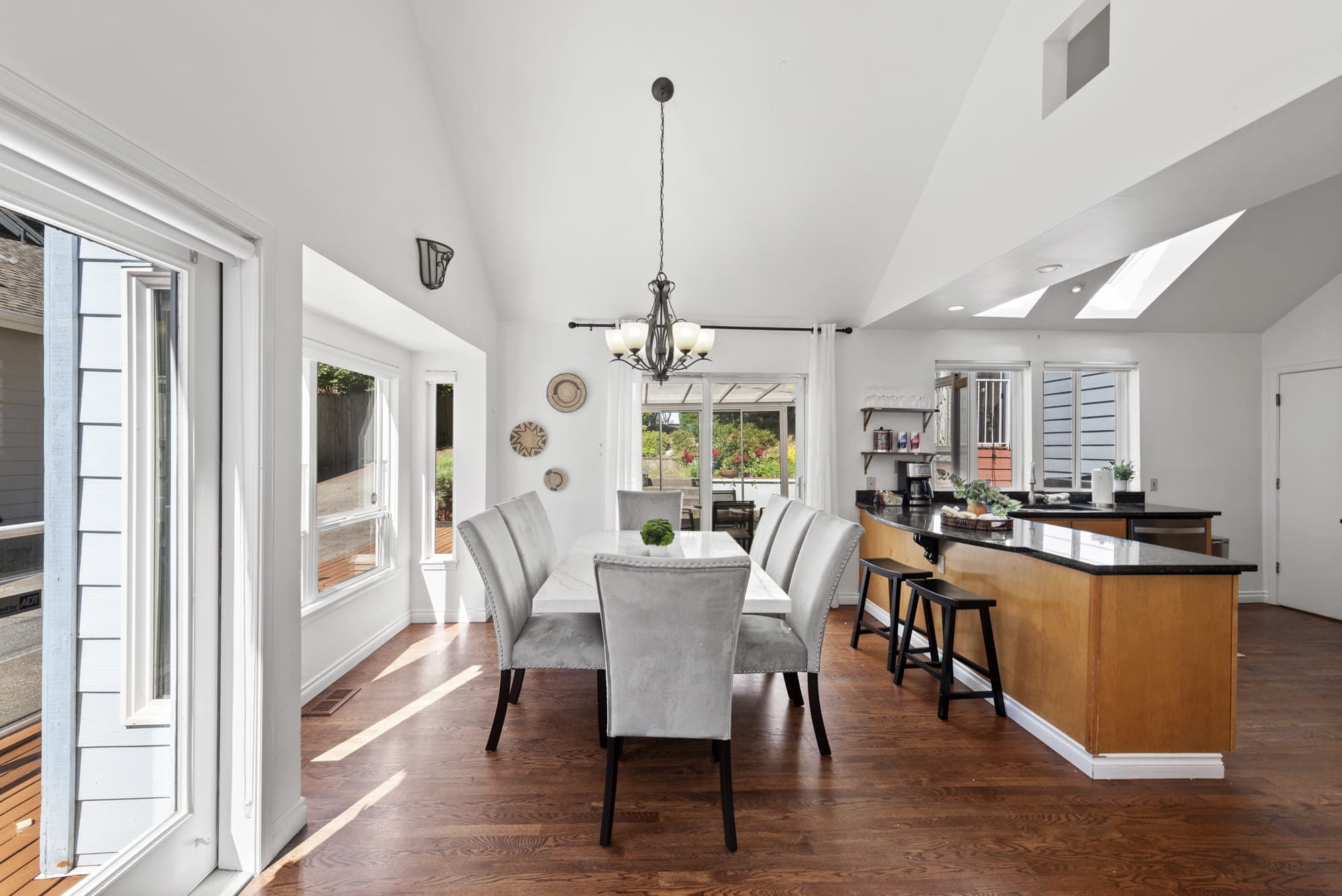 An elegant dining area for 8 adorned by a stylish chandelier and an island next to it for easy access.