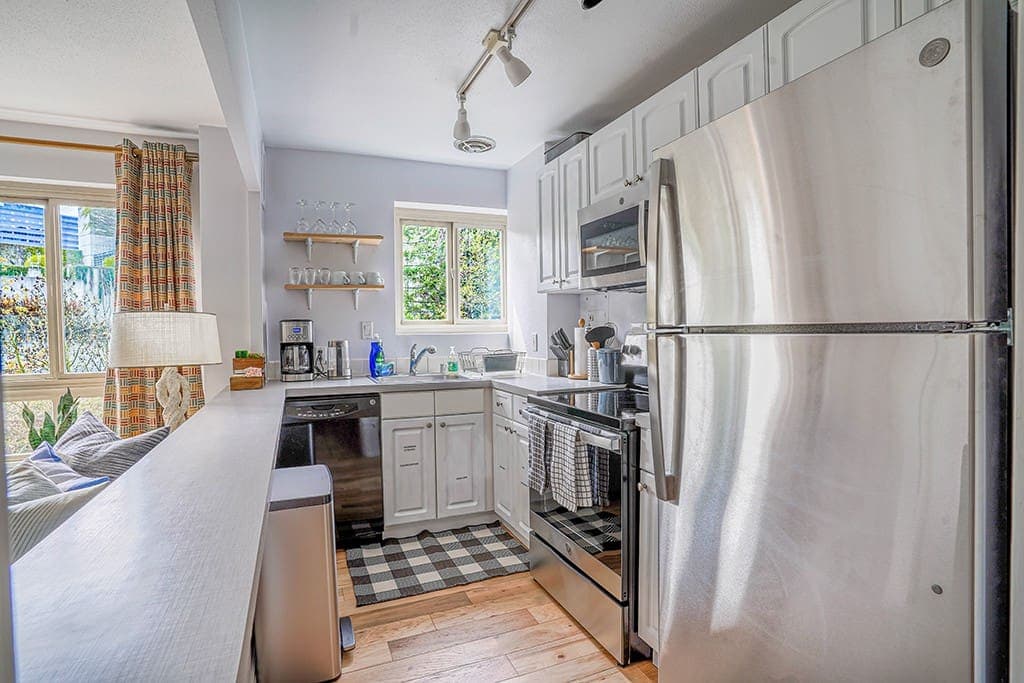 Cook and entertain with ease in this modern, fully equipped kitchen featuring stainless steel appliances, ample counter space, and a convenient open layout that flows seamlessly into the living area.