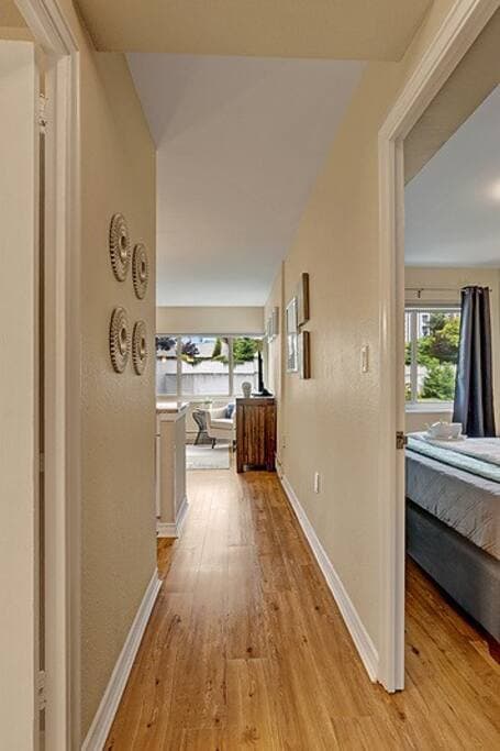This bright hallway features sleek hardwood floors and tasteful wall decor, leading into a cozy living area with ample natural light. Its clean and simple design adds to the welcoming feel of the home