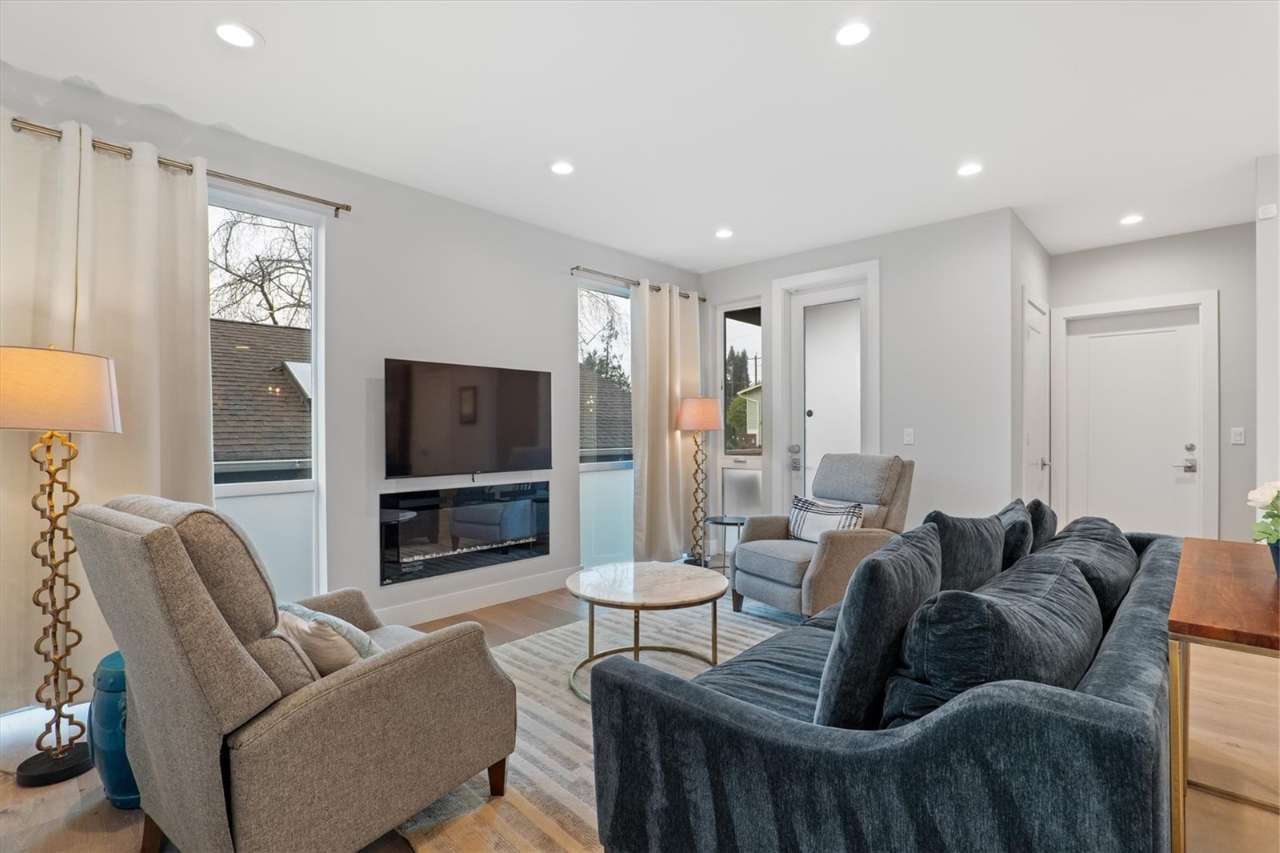 Cozy and elegant living room featuring a plush navy velvet sofa, modern armchairs, a marble coffee table, wall-mounted TV, and built-in fireplace—perfect for relaxing in style.