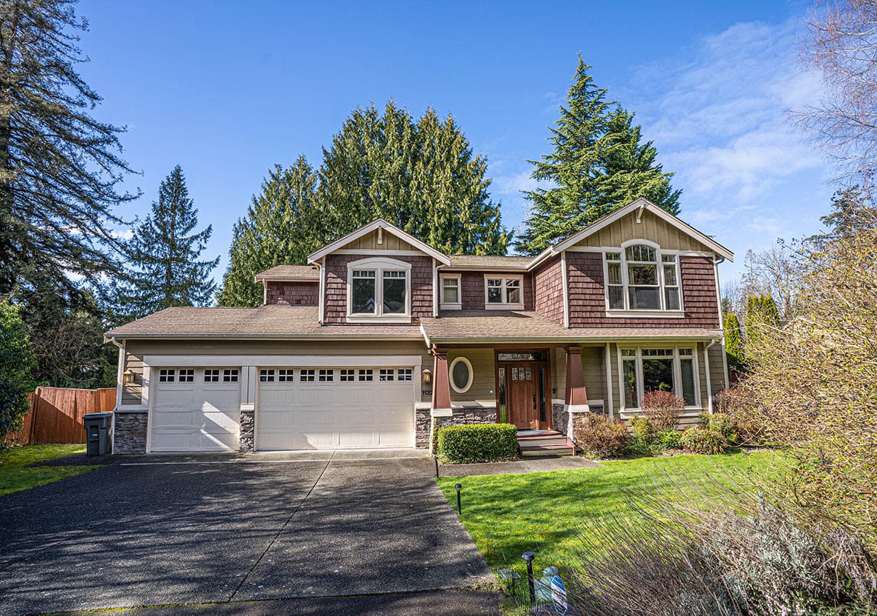 Stunning two-story craftsman-style home features a spacious three-car garage, charming front porch, and is nestled in a lush, tree-lined setting for ultimate privacy and curb appeal.