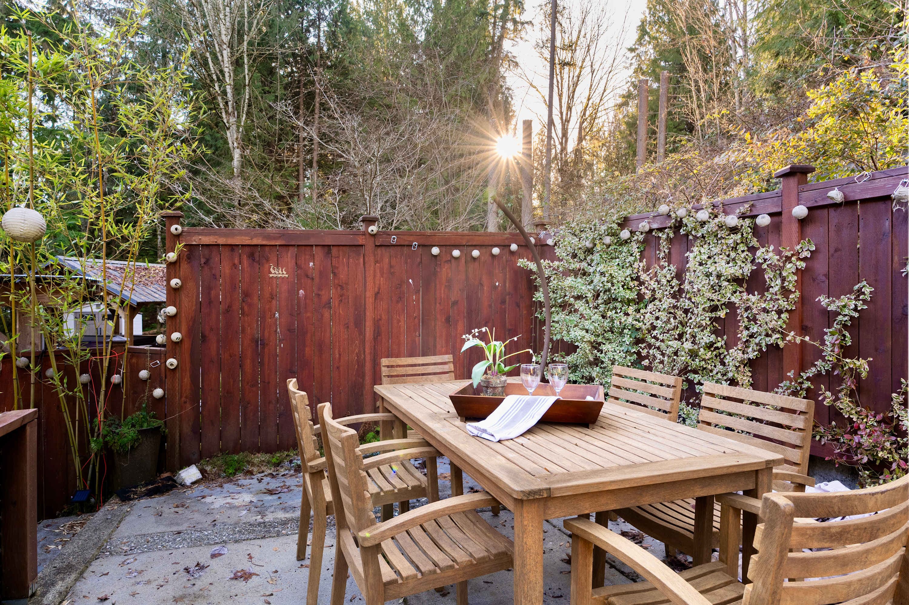 The intimate backyard, complete with a rustic wood table that comfortably seats 6, sets the perfect scene for sharing meals, laughter, or enjoying a serene evening under the open sky.
