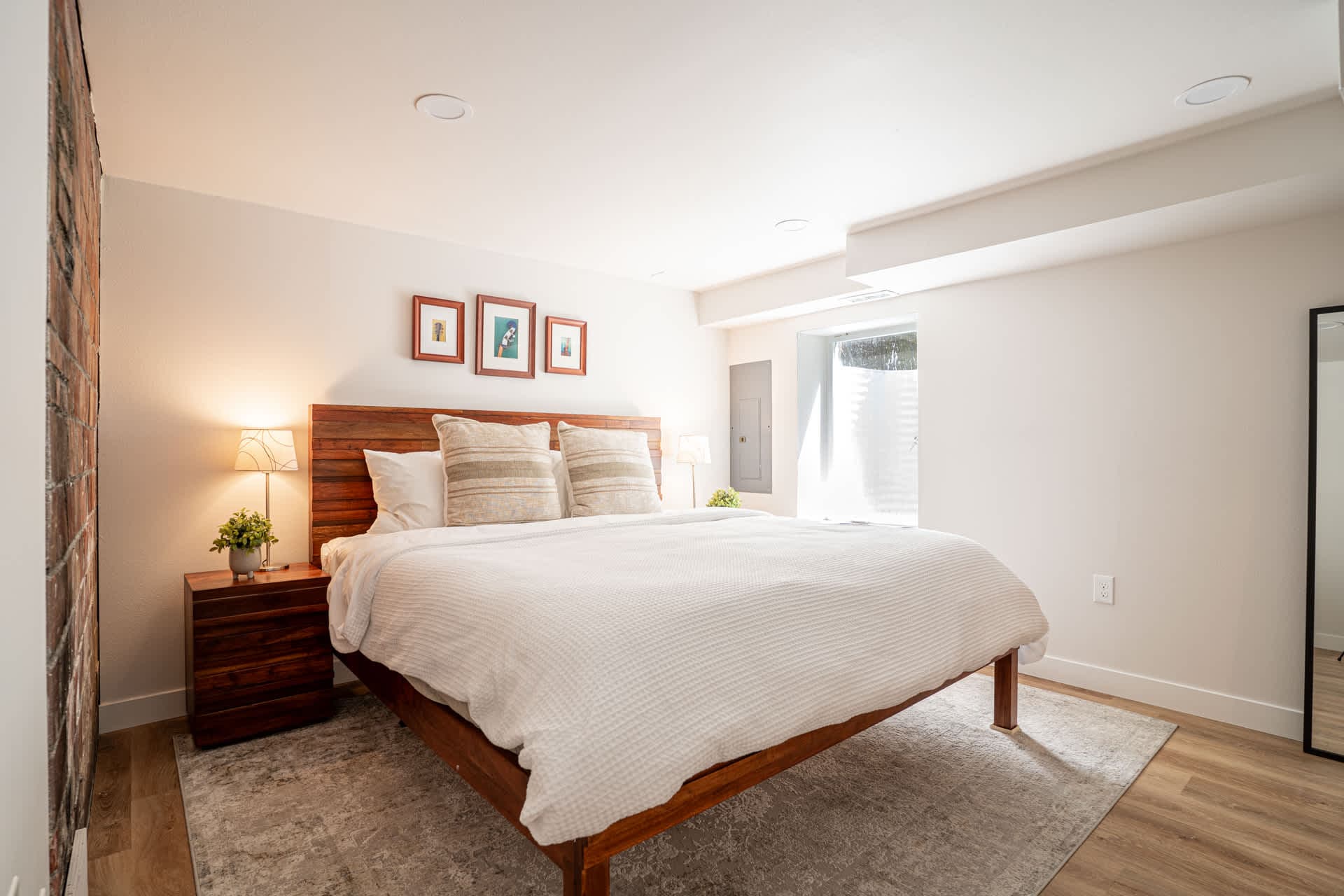 Unwind in this serene, sunlit bedroom where soft textures, warm wood accents, and calming tones invite you to sink into restful slumber after a day of exploring.